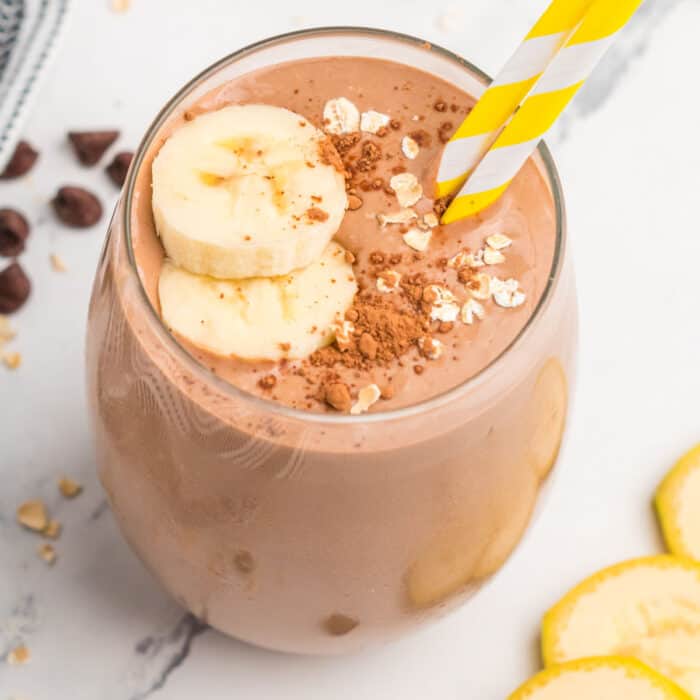 square image of chocolate peanut butter banana smoothie with banana slices, oats, and cocoa powder on top