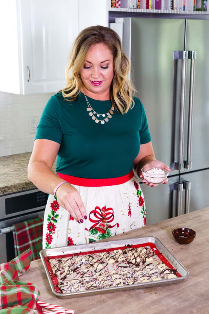 woman sprinkling crushed peppermints on cookies