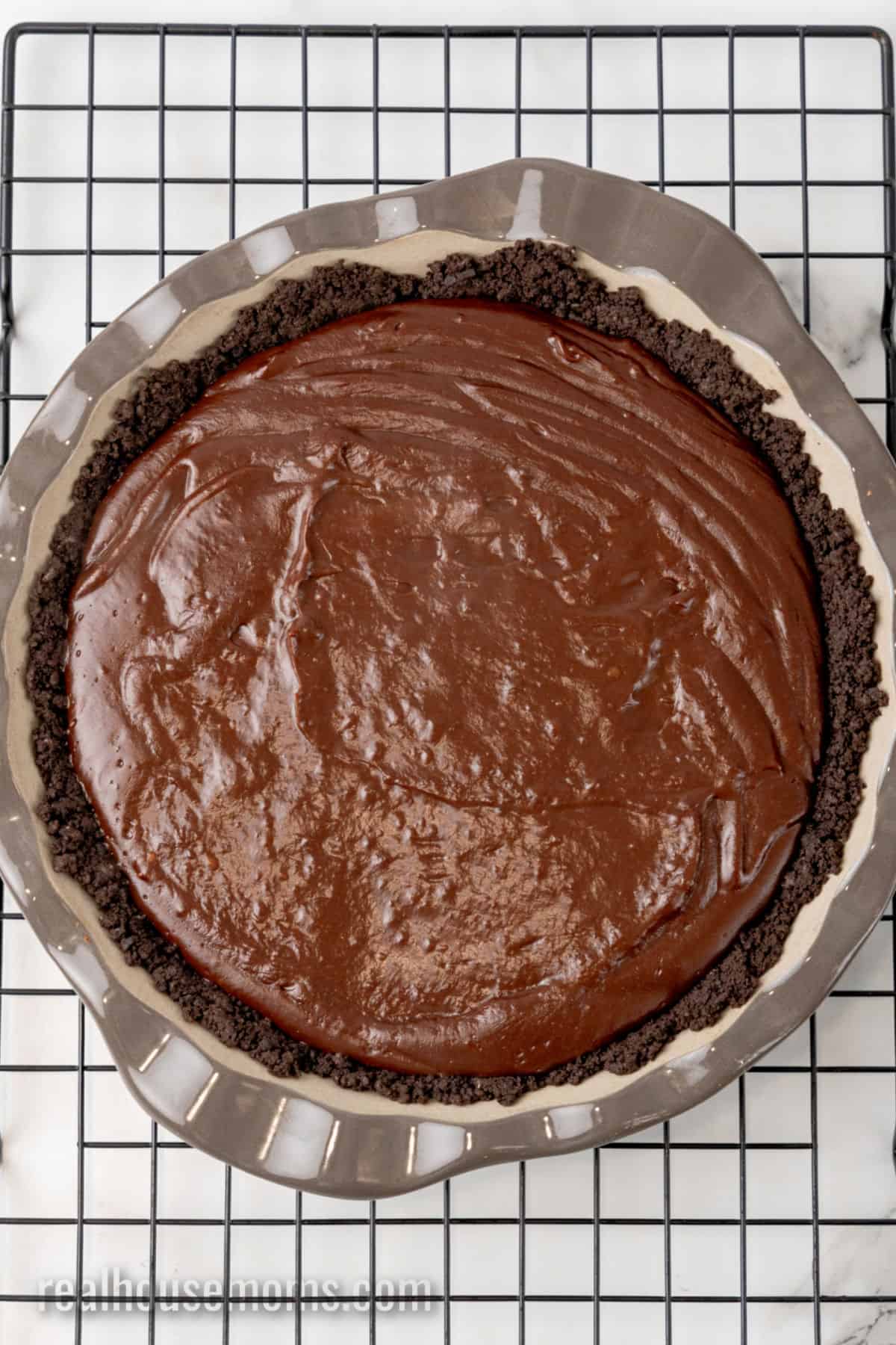 homemade chocolate pudding filling in an Oreo pie crust on a wire rack