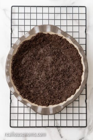 baked Oreo pie crust in a deep dish pie plate on a wire rack