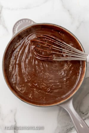 homemade chocolate pudding in a saucepan with a whisk