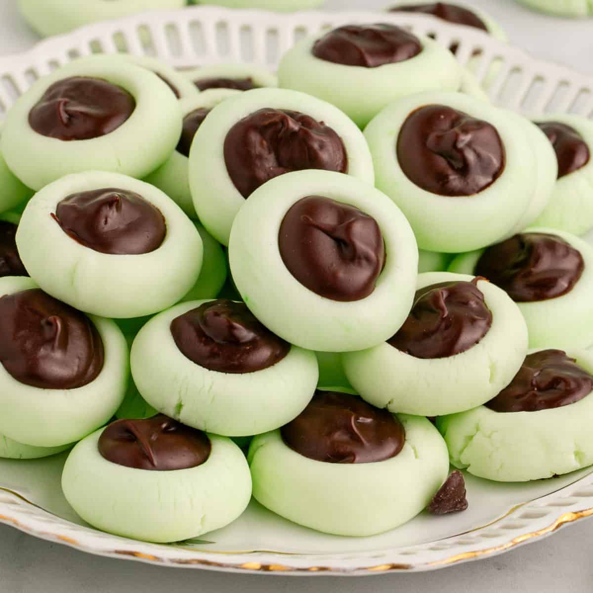 square image of chocolate thumbprint cream cheese mints piled on a plate