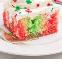 slice of christmas poke cake topped with cool whip and sprinkles with recipe name at the bottom