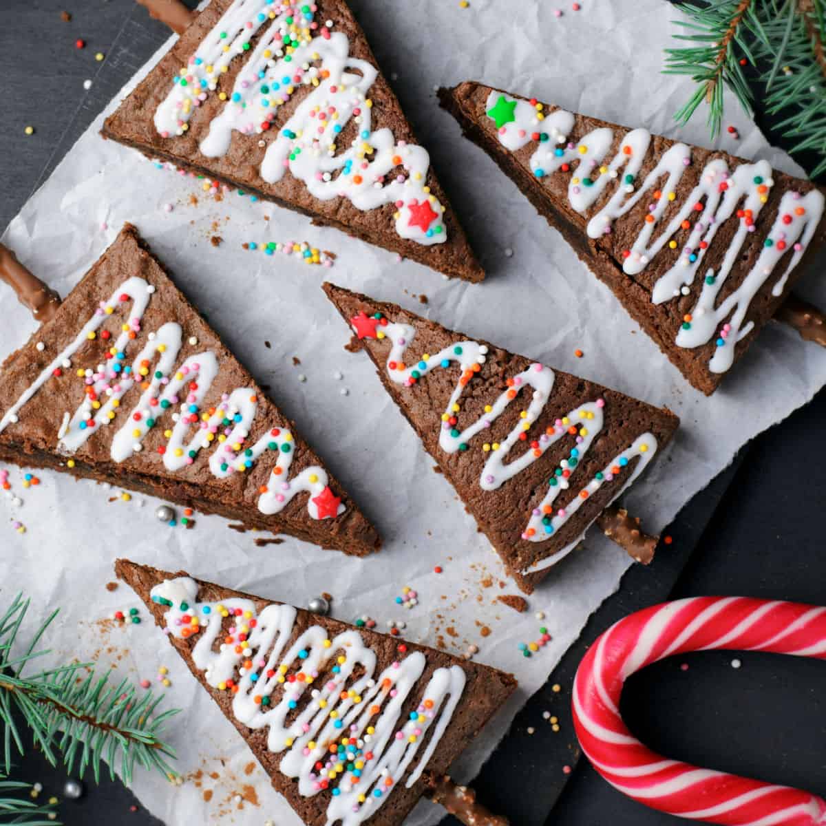 square image of christmas tree brownies laid out on a piece of parchment paper next to a candy cane
