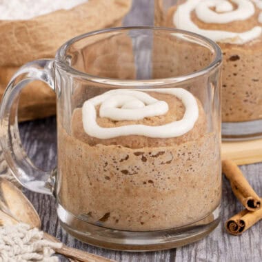 square image of cinnamon roll mug cake in a glass mug