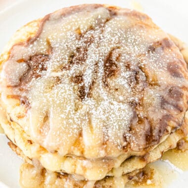 square image of a stack of cinnamon roll pancakes with cream cheese glaze