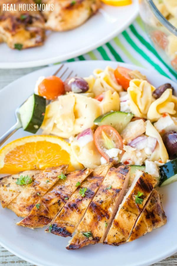 sliced grilled chicken on a plate with pasta salad