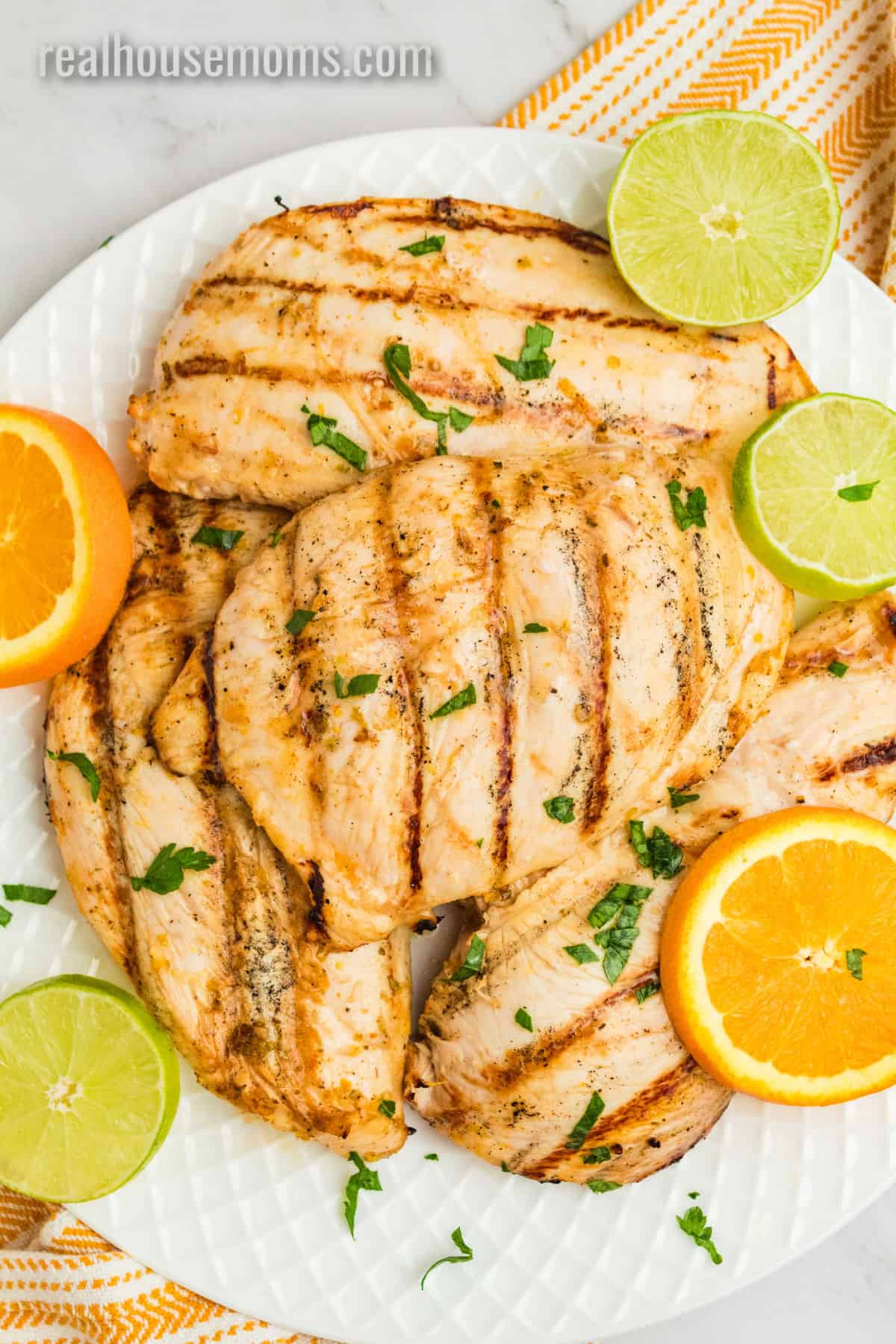 grilled citrus marinated chicken breasts on a platter with orange and lime slices
