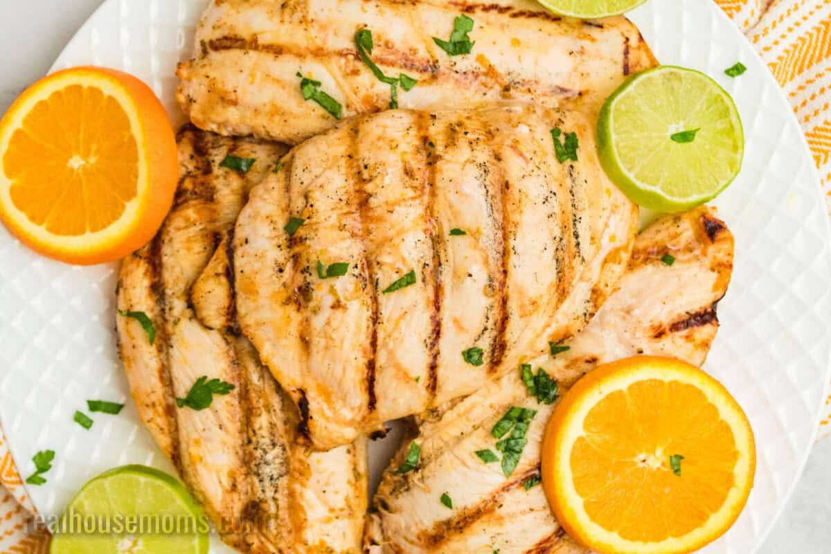 grilled citrus chicken on a platter next to lime and orange slices
