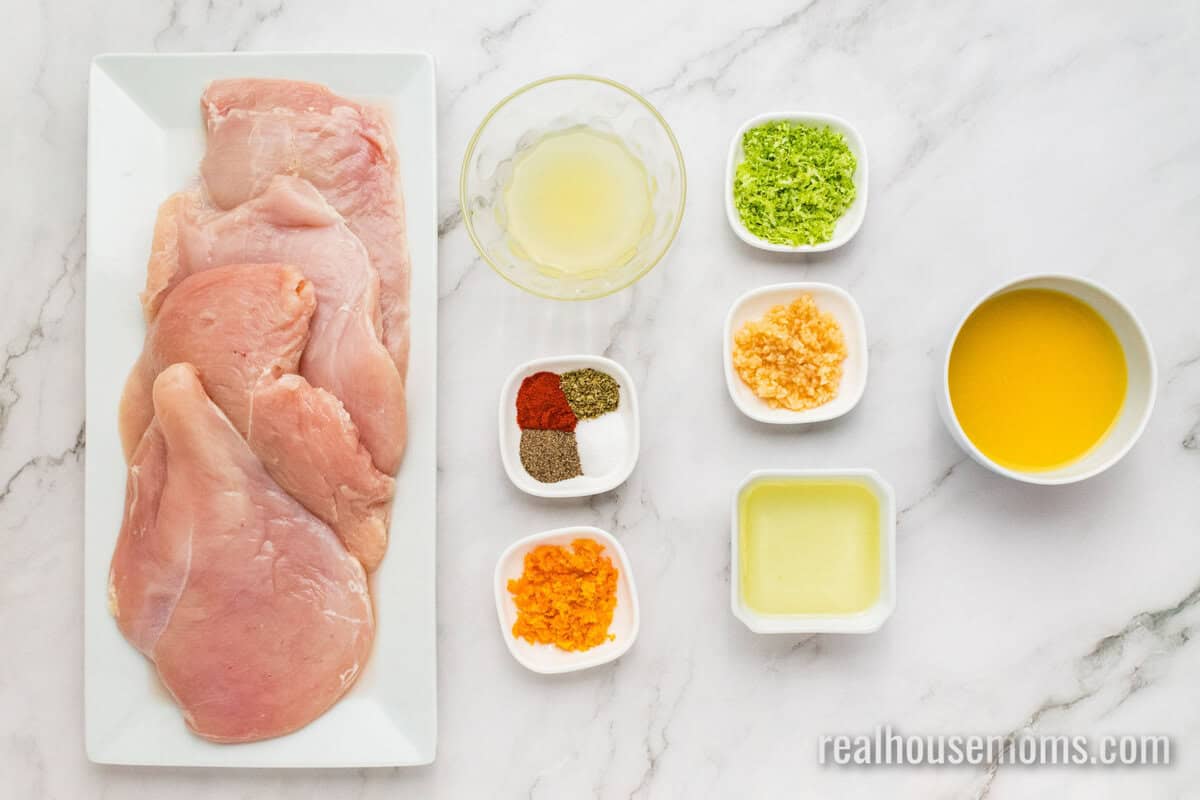 raw chicken breasts on a platter next to ingredients to make Citrus Chicken Breast Marinade in bowls on a counter