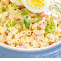 bowl of macaroni salad with a hard boiled egg cut in half on top with recipe name at bottom