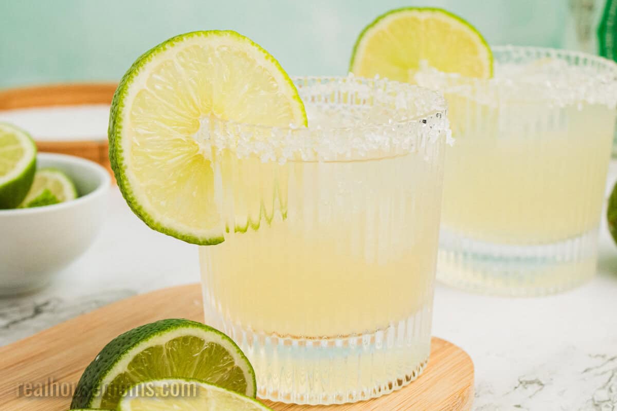 two margaritas with salt rims and a lime wheel for garnish