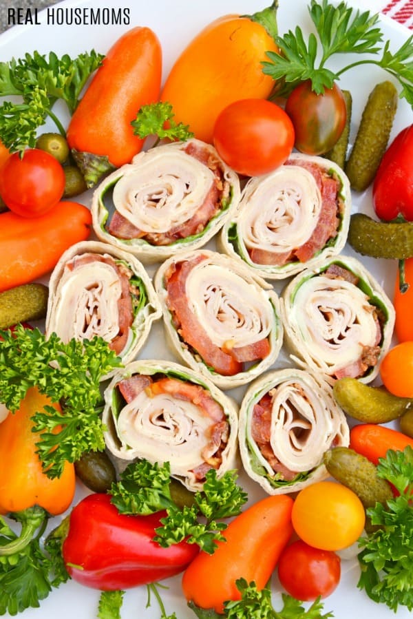 club sandwich pinwheels on a serving platter with mini peppers and pickles