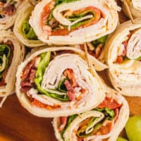 club sandwich pinwheels on a wooden plater with recipe name at the bottom