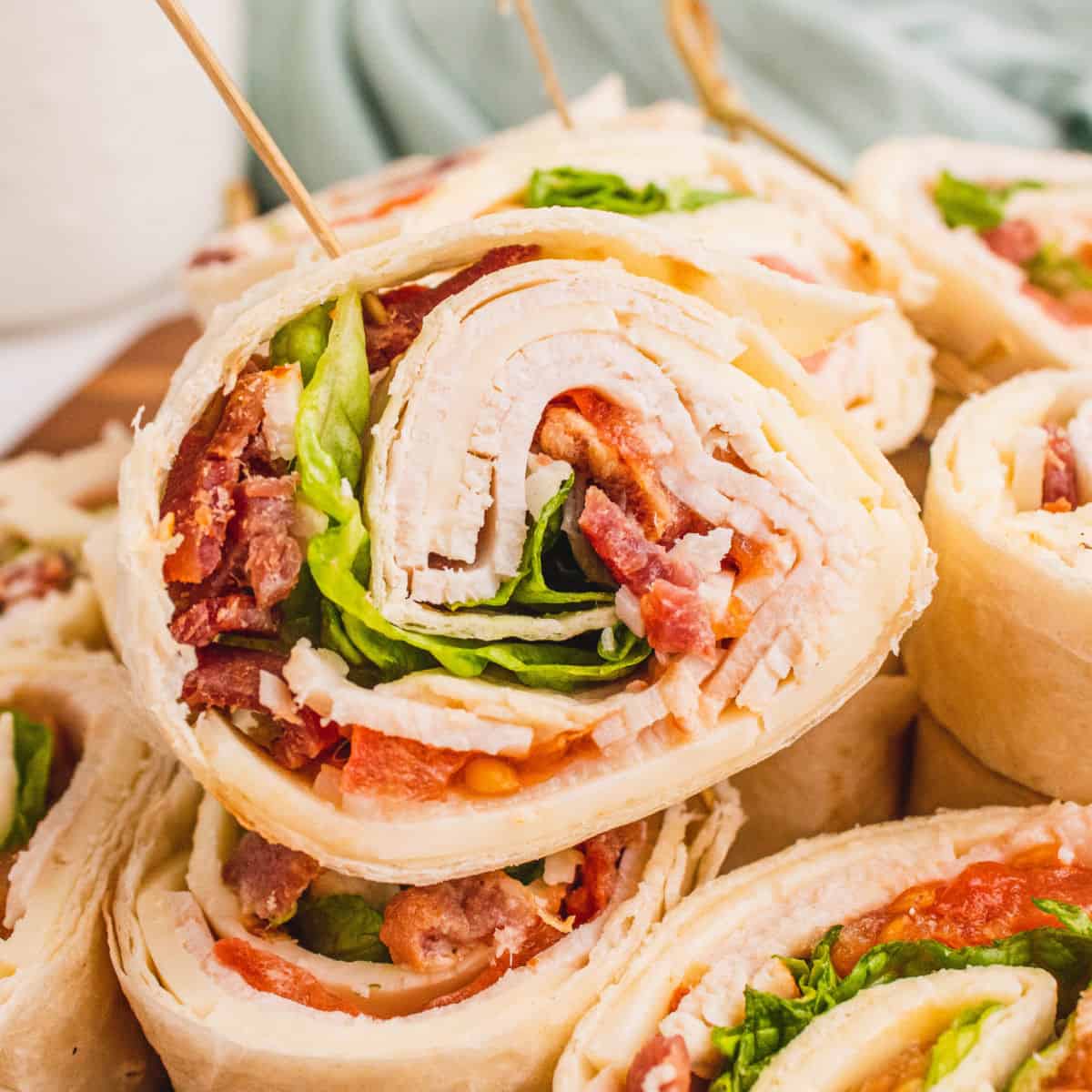 square close up image of a club sandwich pinwheels on a platter