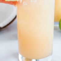 coconut tequila and grapefruit cocktail with grapefruit and lime slices with recipe name at the bottom