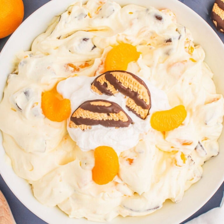 square image of cookie salad in a serving bowl with cool whip, cookies, and oranges for garnish