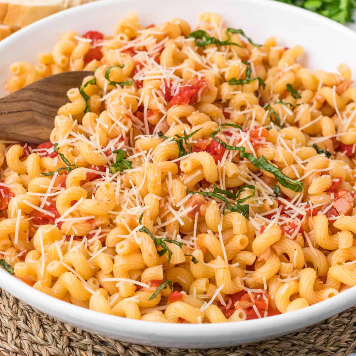 square image of copycat carrabba's cavatappi amatriciana in a serving bowl with a wooden spoon