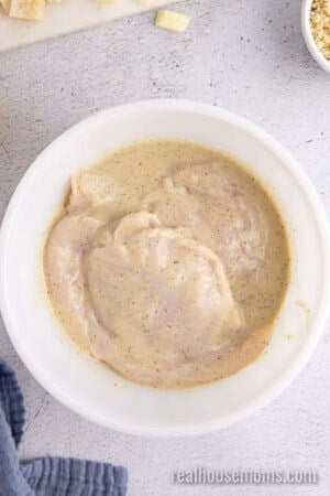 chicken breasts in a bowl of longhorn parmesan chicken marinade