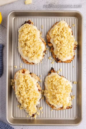 seared chicken breasts topped with ranch cheese sauce and panko breadcrumbs on a baking sheet