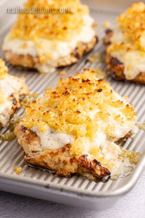 angled view of broiled copycat longhorn parmesan crusted chicken on a baking sheet