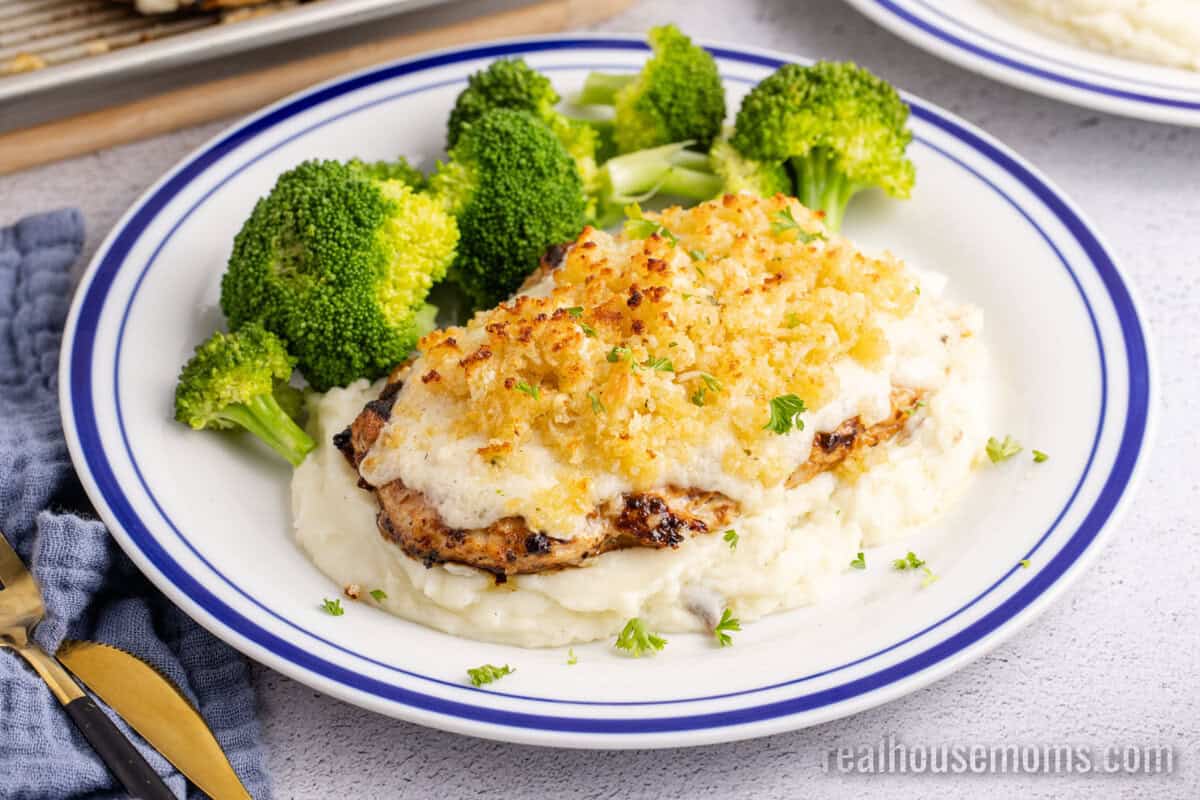 Copycat Longhorn Parmesan Crusted Chicken served over mashed potatoes with a side of broccoli on a dinner plate