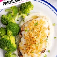 looing down at copycat longhorn parmesan crusted chicken served over mashed potatoes with some broccoli with a banner looking title of the post at the top og the post in pink and black lettering