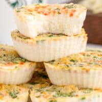 copycat starbucks egg white & roasted red pepper egg bites stacked up on a plate with a bite taken out of one to show the texture with the title of the post in green and black lettering