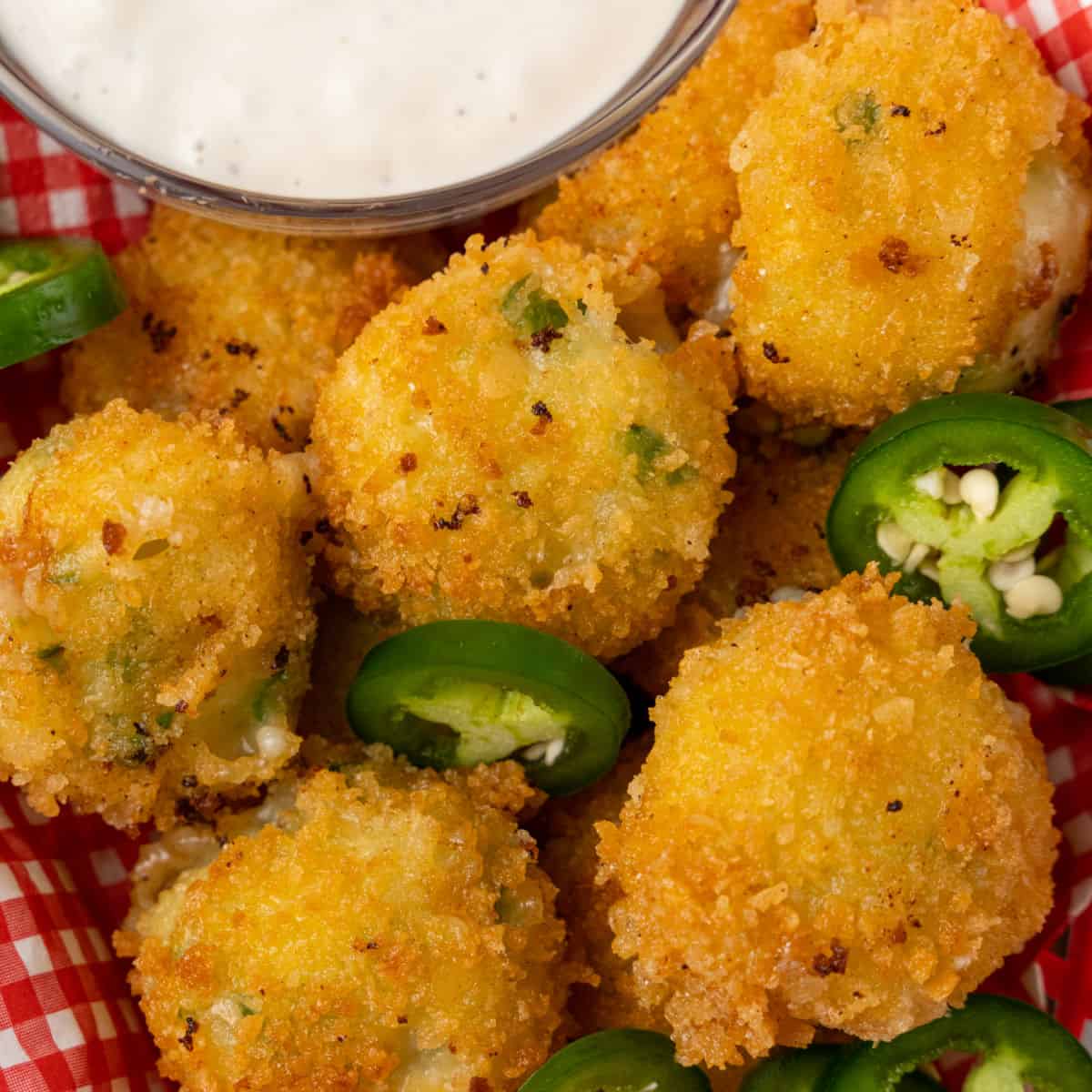 square image of copycat texas roadhouse rattlesnake bites in a basket with jalapeno slices and a bowl of ranch