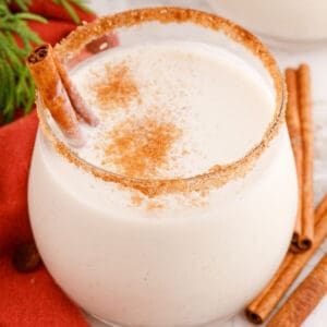 square image of coquito in a stemless wine glasses rimmed with cinnamon sugar