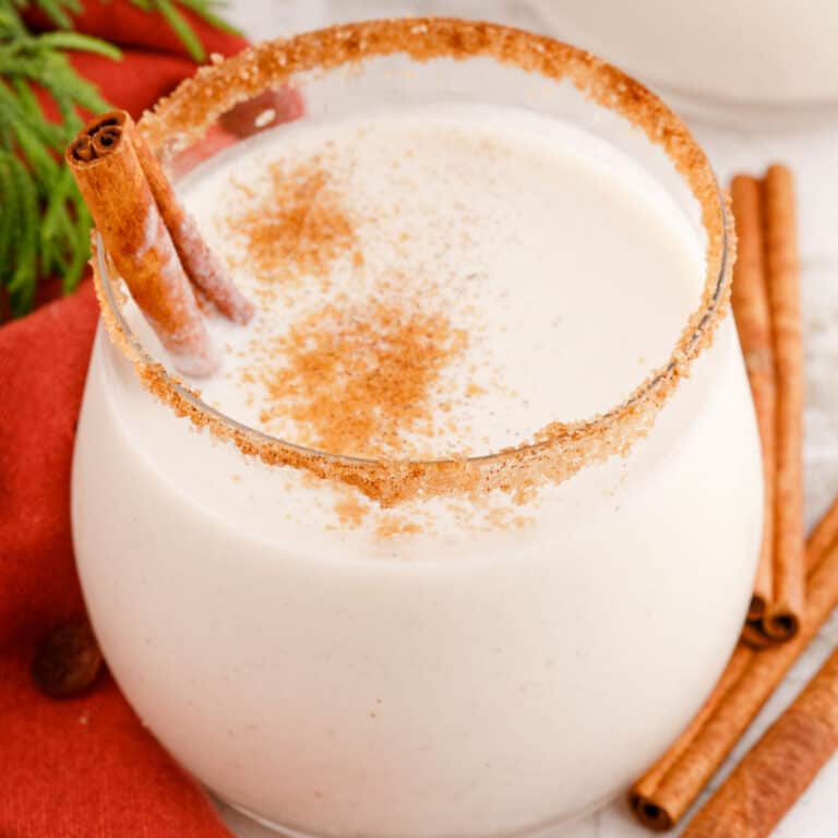 square image of coquito in a stemless wine glasses rimmed with cinnamon sugar