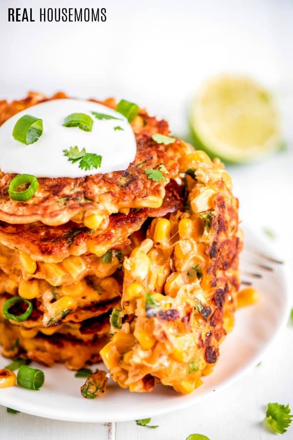 corn fritters on a serving plate topped with sour cream