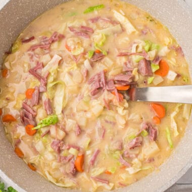 square image of corned beef and cabbage chowder in a large pot with a ladle