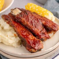 sauce image of country style pork ribs on a plate with mashed potatoes and corn on the cob