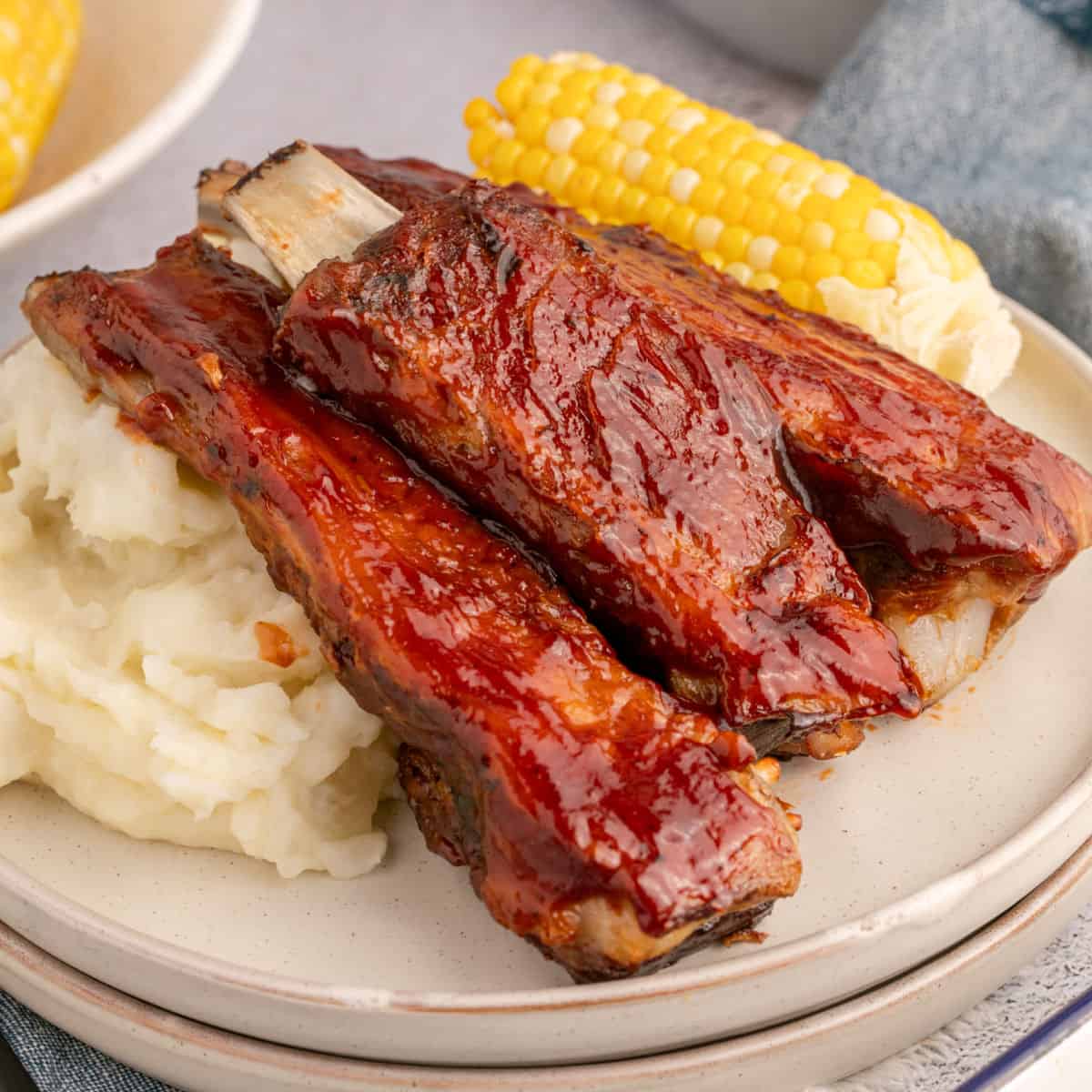 sauce image of country style pork ribs on a plate with mashed potatoes and corn on the cob