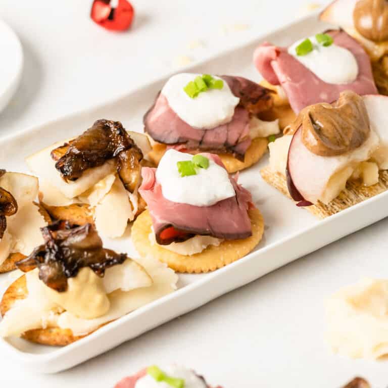 square image of three types of cracker canapes on a platter