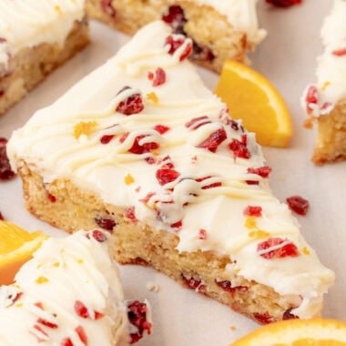 square image of a cranberry bliss bar next to fresh orange slices