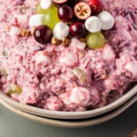 bowl of cranberry fluff with fruit and marshmallows on top with recipe name at the bottom