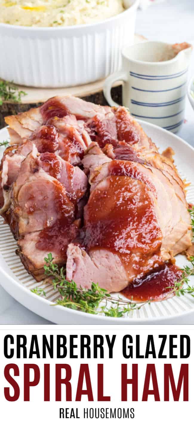 spiral cut ham with cranberry glaze on a platter with thyme sprigs