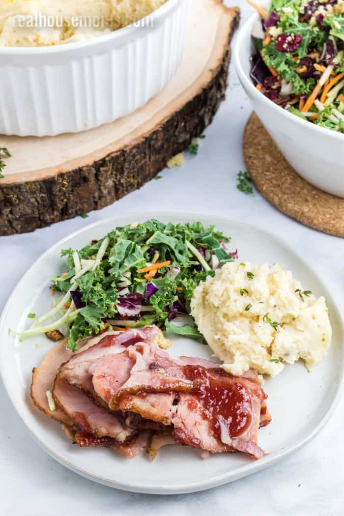 cranberry glazed ham served on a plate with mashed potatoes and salad