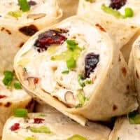image of cranberry pecan chicken salad pinwheels on a plate with the title of the post on top of image in cranberry and black lettering