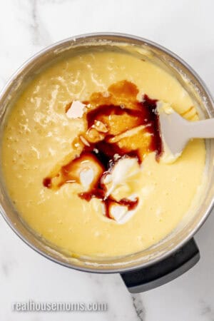 vanilla, sour cream, and eggs added to butter, cream cheese, and butter in a mixing bowl