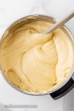 cream cheese pound cake batter in a metal mixing bowl with a rubber spatula