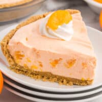 slice of creamsicle chiffon pie on a small plate with the pie behind it with recipe name at bottom