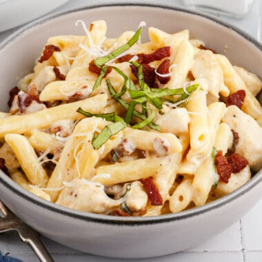 square image of creamy chicken bacon ziti in a bowl next to a fork