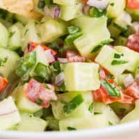 tortilla chip being dipped into creamy cucumber salsa with recipe name at the bottom
