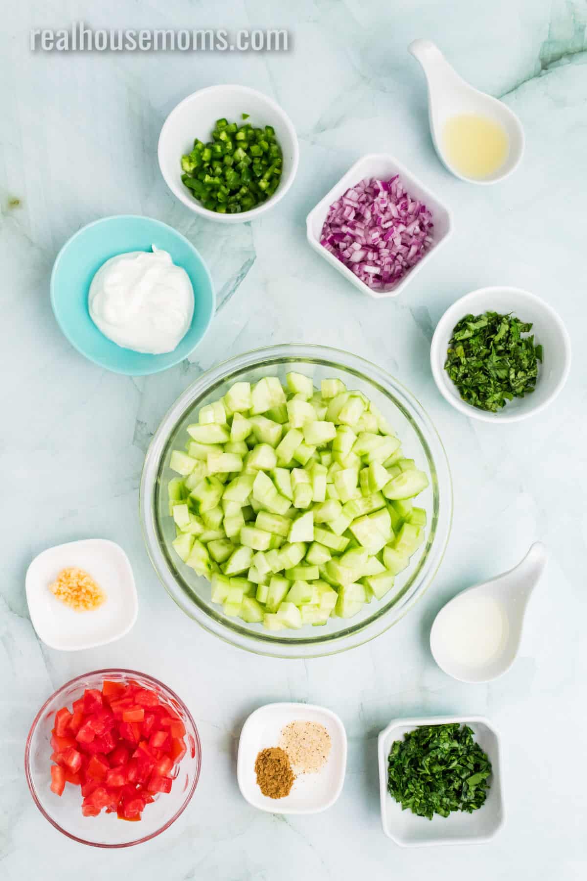 ingredients to make creamy cucumber salsa in bowls on a counter