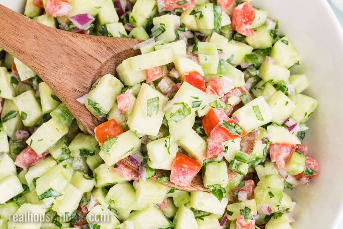 wooden spoon in a serving bowl of creamy cucumber salsa