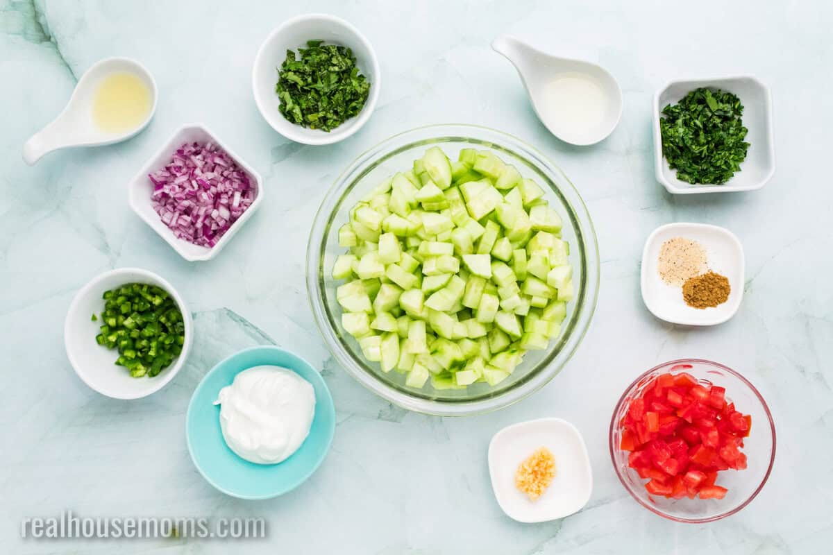 ingredients to make cucumber salsa in bowls on a counter
