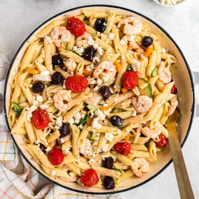 square image of creamy greek shrimp pasta in a dutch oven
